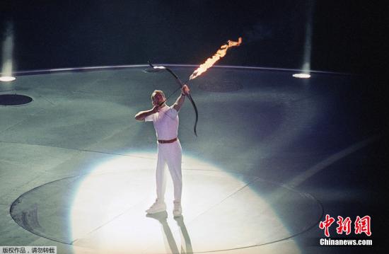 资料图:巴塞罗那开幕式上的点火者从轮椅上用箭接过火炬上的火种,“射燃”了火炬台。 资料图:巴塞罗那开幕式上的点火者从轮椅上用箭接过火炬上的火种,“射燃”了火炬台。